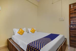 1 dormitorio con 1 cama con almohadas amarillas y azules en OYO Hotel Shivaj, en Indore