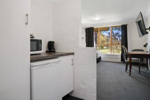 a kitchen with a microwave and a room with a table at Golf Place Inn Wollongong in Primbee