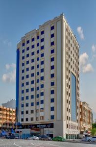 a tall white building with a lot of windows at Wescott Hotel in Dubai