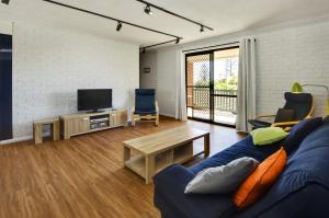 a living room with a blue couch and a tv at Azure Beach Stop in South West Rocks