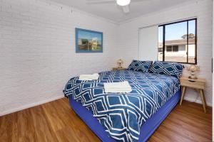 a bedroom with a bed and a desk and a window at Azure Beach Stop in South West Rocks