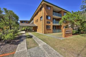a large brick building with a lawn in front of it at Azure Beach Stop in South West Rocks