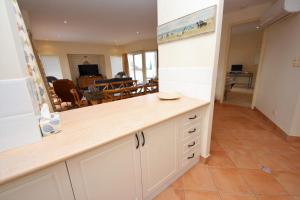 a kitchen with white cabinets and a living room at Seabreeze 3 at South West Rocks - No Sheets or Towels Provided in South West Rocks