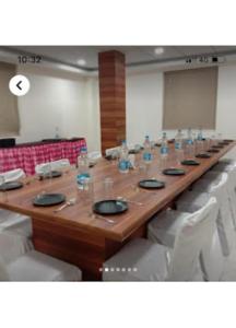 a long wooden table in a room with white chairs at Shri Jagannath Hotel,Cuttack in Cuttack