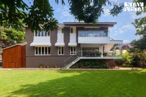a house with a green lawn in front of it at StayVista's House Of J - Embrace Leisure with Lawn, Pool, and Gazebo in Lonavala