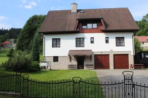 duży biały dom z czarnym płotem w obiekcie Penzion Mühl w mieście Bedřichov