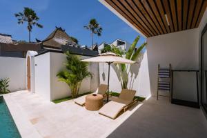 a patio with an umbrella and chairs and a pool at Unity Villas Canggu in Canggu