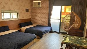 a room with two beds and a table and a window at 若華軒民宿Ruohuaxuan in Fangliao