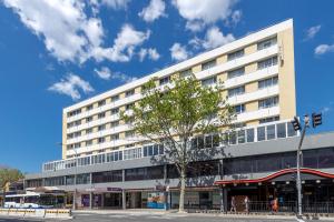 un gran edificio blanco con un árbol delante en Park Regis Concierge Apartments en Sídney