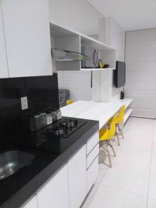 eine Küche mit Spüle und Theke mit gelben Stühlen in der Unterkunft O melhor de Maceió, Edf Time, Ponta verde. in Maceió