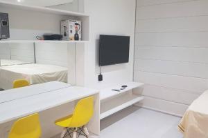 ein weißer Raum mit gelben Stühlen und einem Fernseher in der Unterkunft O melhor de Maceió, Edf Time, Ponta verde. in Maceió
