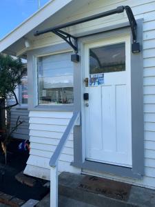 a porch with a white door and a sign on it at RS Two-Bedroom Apartment in Palmerston North