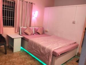 um quarto com uma cama rosa e luz verde em Greenland gokarna Ac and Non Ac em Gokarna