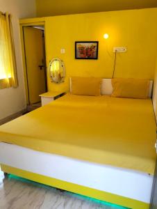 uma cama num quarto com uma parede amarela em Greenland gokarna Ac and Non Ac em Gokarna