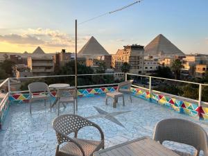 a patio with chairs and tables and the pyramids at Matto Pyramids Inn in Cairo