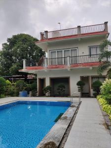 a house with a swimming pool in front of it at Lotuslap Resort in Rehti