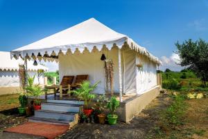 une tente blanche avec une chaise et des plantes dans l'établissement Lotuslap Resort, à Rehti