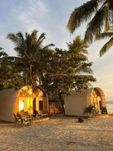 a couple of tents on a beach with palm trees at Siquijor Glamping Village in San Juan