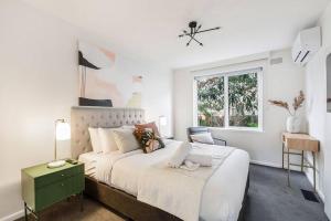 - une chambre blanche avec un grand lit et une fenêtre dans l'établissement Urban Green - Stylish Courtyard Haven off Malvern Rd, à Melbourne