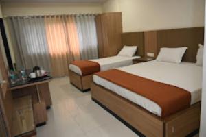 a hotel room with two beds in a room at HOTEL PRITAM PARK, Jalgaon, Maharashtra in Jālgaon