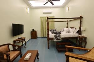a living room with a bed and a tv at Le Colonial Suites in Puducherry