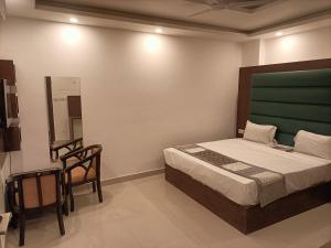 ein Schlafzimmer mit einem Bett, einem Stuhl und einem Spiegel in der Unterkunft Hotel Ambience Palace Near IGI Airport Delhi in Neu-Delhi