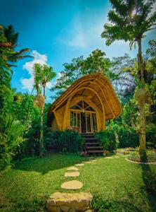 una casa de bambú en medio de un jardín en Arcada Bali Bamboo House en Sidemen
