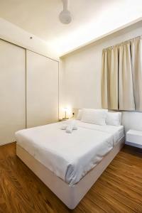een witte slaapkamer met een groot bed met witte lakens bij Beacon Executive Suite George Town in George Town