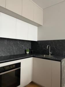 a kitchen with white cabinets and a sink at Dineikos apartamentai in Druskininkai +2 photos