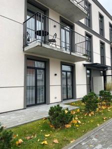 a building with a balcony and a yard at Dineikos apartamentai in Druskininkai