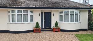 a white house with two windows and two plants at The Golf Studio Woodhall Spa in Woodhall Spa