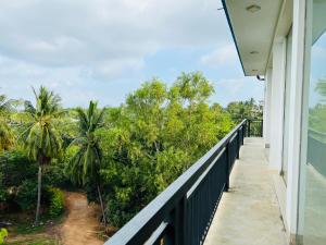 een balkon van een huis met uitzicht op bomen bij Esha Beach Resort Rooms in Trincomalee