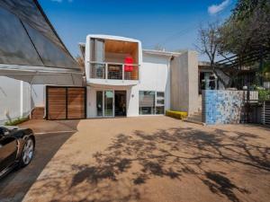 een huis met een balkon en een auto die ervoor geparkeerd staat bij Milner Fashion House in Pretoria