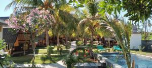 a garden with palm trees and chairs and a swimming pool at Pandan Bungalow in Gili Air