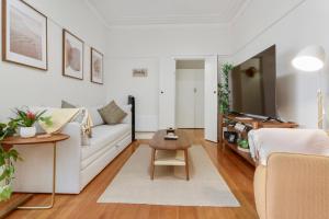 sala de estar con sofá blanco y TV en Sophisticated East Melbourne Retreat, en Melbourne