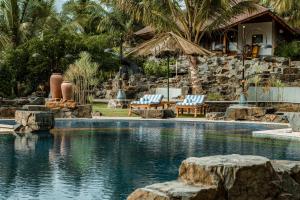 una piscina con 2 sillas y una casa en ama Stays & Trails Eden Farms Paradise, Goa, en Goa