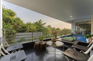 a room with a balcony with chairs and a table at Lavish Apartments with Swimming Pool near Candolim Beach in Marmagao