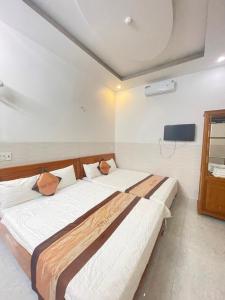 a bedroom with two beds and a tv on the wall at Hưng Phát Hotel in Phu Yen