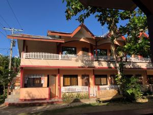 uma casa com uma árvore em frente em JBR Tourist Inn - Port Barton em Itaytay