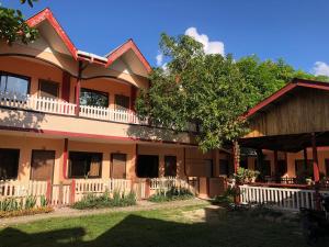 a large house with a tree in front of it at JBR Tourist Inn - Port Barton in Itaytay