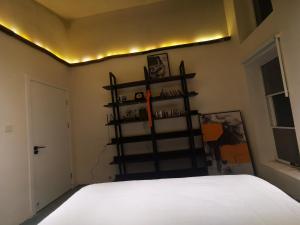 1 dormitorio con cama blanca y estante para libros en 此时此刻民宿This Moment B&B, en Miyun