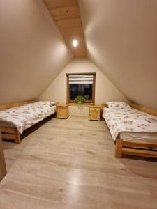 a attic room with two beds and a window at Domek Aniula in Istebna