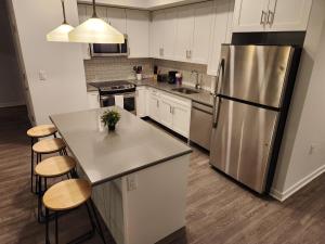 a kitchen with a stainless steel refrigerator and wooden floors at Modern 2 bed apt, mins to NYC! in Jersey City
