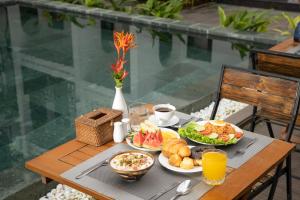 una mesa con platos de comida y bebidas. en Crony Villa - STAY 24H en Hoi An
