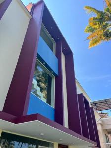 a purple and white building with a palm tree at BAVA Lalitha Retreat Center Varkala in Varkala