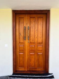 una gran puerta de madera con una alfombra delante en BAVA Lalitha Retreat Center Varkala en Varkala