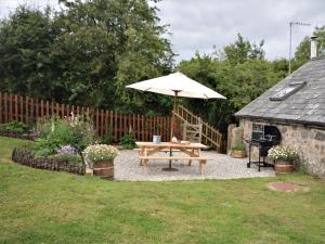 a picnic table and an umbrella in a yard at 2 Bed in Dartmoor National Park 63337 in Spreyton