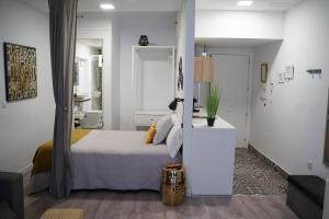 a white bedroom with a bed and a living room at Apartamentos Suites Cariátide in Plasencia