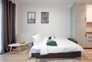 a white bedroom with a bed and a table at Żelazna Modern Studio in Poznań