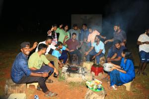 a group of people sitting around a fire at Rainbow Residency in Yelagiri